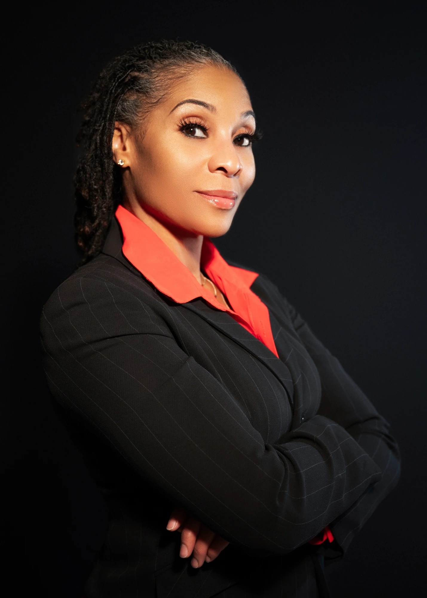 Adina Howard, Founder of SHE Global™ Institute, in a black pinstripe suit and red collared shirt.